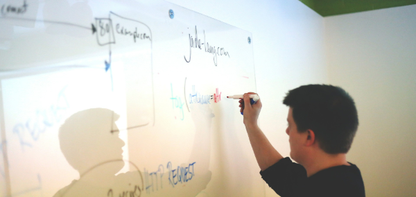 A human writting something on a marker board.